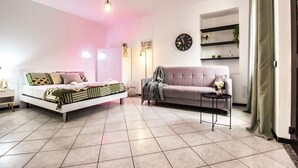A modern bedroom with a bed, a sofa, a small table, and a wall clock. - Volta hub- parking lot and garden Lake Como 7min (Como)
