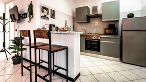 A modern kitchen with a central island, stainless steel appliances, and a bar stool. - Volta hub- parking lot and garden Lake Como 7min (Como)