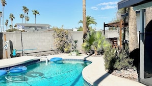 A swimming pool with clear blue water, surrounded by palm trees and a wooden deck. - Family-friendly 4 bd with sparkling free heated pool, , games. ASU close (Tempe)