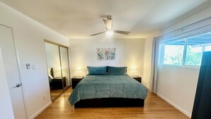 A bedroom with a bed, two bedside tables, a ceiling fan, a window, and a door. - Family-friendly 4 bd with sparkling free heated pool, , games. ASU close (Tempe)