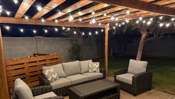 An outdoor patio with wicker furniture, string lights, and a wooden pergola. - Family-friendly 4 bd with sparkling free heated pool, , games. ASU close (Tempe)
