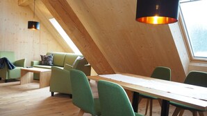 Un intérieur moderne avec un plafond en pente, des poutres en bois, une table à manger avec des chaises et un canapé.