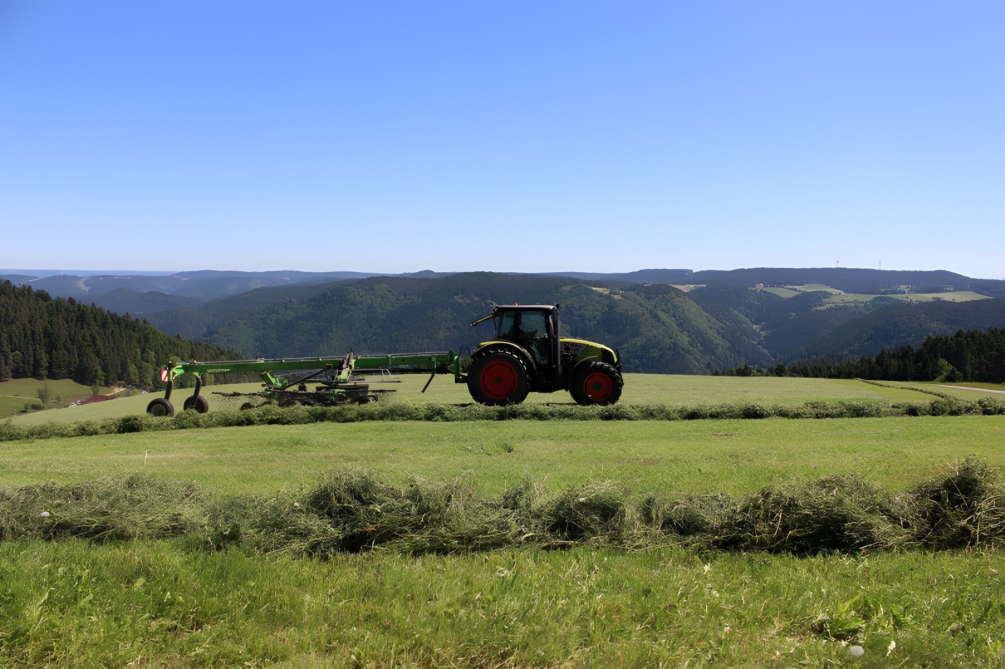 A tractor in a field with rolling hills and a clear sky.