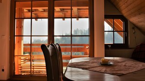 A room with a large window, a wooden table, and a chair.