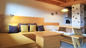 A wooden interior with a sofa, a wooden table, and a kitchen area. - Apartment 'Pfiffikus' with Mountain View, Shared Terrace and Wi-Fi (Schonach)