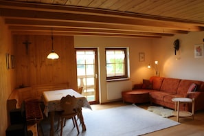 Ein Holzinterieur mit Esstisch, Stühlen, einer Couch und einem kleinen Beistelltisch.