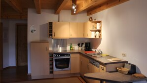 A compact kitchen with wooden beams, a built-in oven, a sink, and a coffee maker.