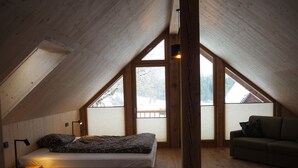 Camera mansarda con letto, divano e ampie finestre.