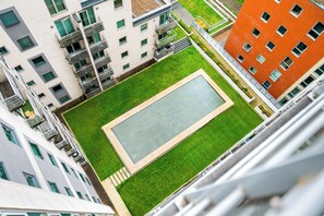 Ein Hochhaus mit mehreren Balkonen und einem Innenhof, der einen rechteckigen Pool beinhaltet.