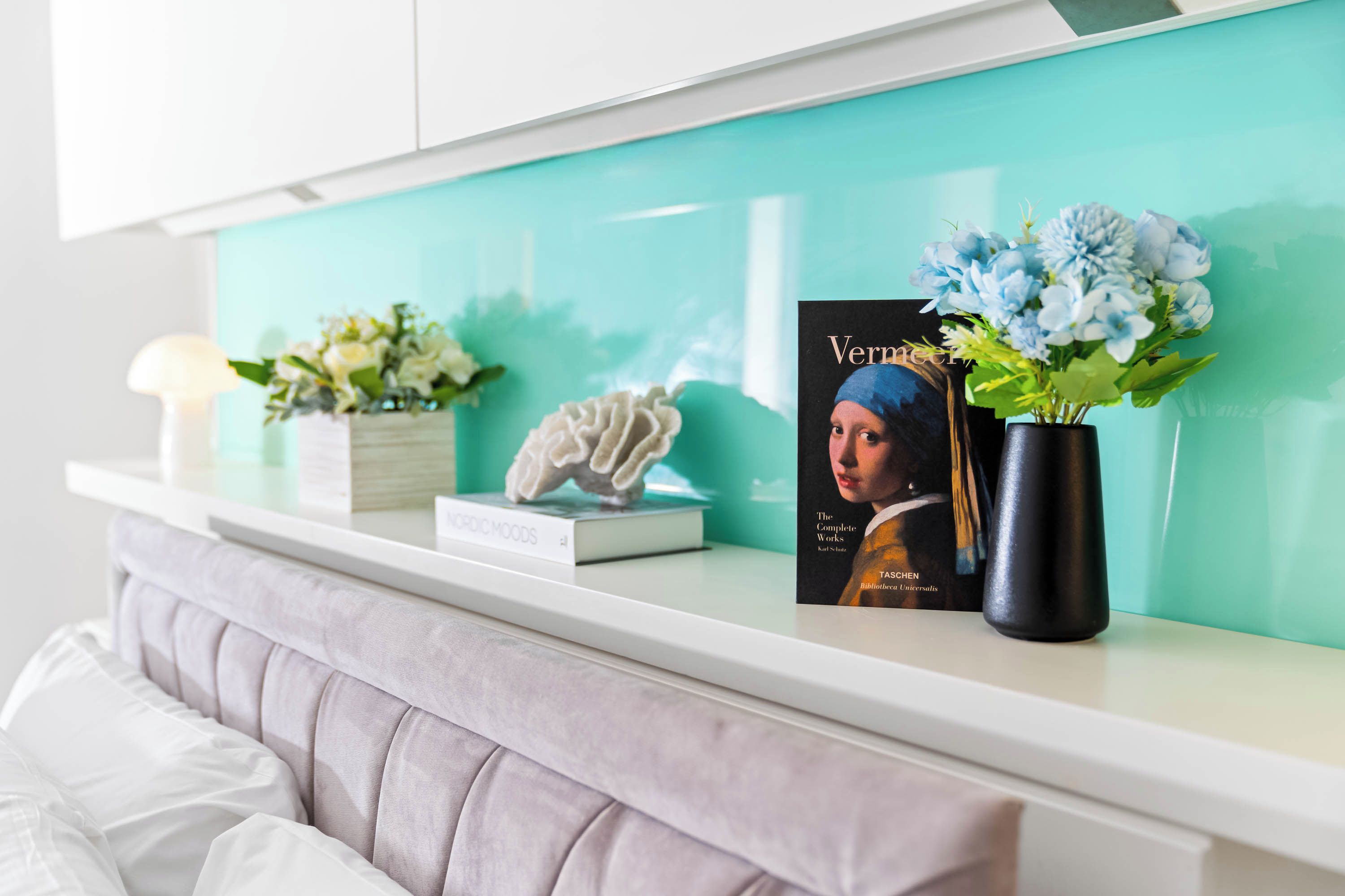 A bookshelf with a book titled 'Vermelho' and a vase with flowers.