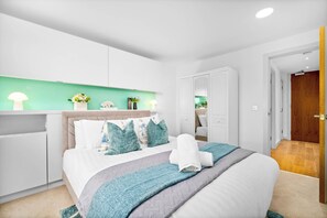 Ein modernes Schlafzimmer mit Bett, Nachttischen, einem Kleiderschrank und einer Wand mit grüner Beleuchtung.
