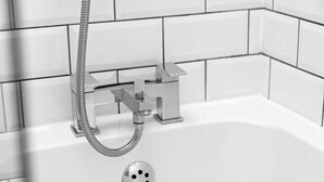 Un bagno moderno con doccetta e pannello comandi cromati, pareti piastrellate di bianco e una vasca da bagno.