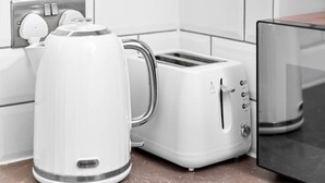 Una cucina con bollitore bianco, tostapane e forno a microonde.