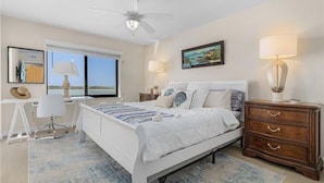 A bedroom with a bed, bedside tables, a desk, and a chair.