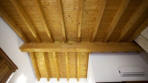 Une pièce avec un haut plafond en bois, des murs blancs et un appareil de climatisation blanc.