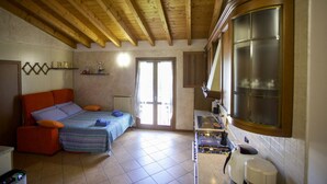 Une chambre avec un lit, une petite kitchenette et une fenêtre.