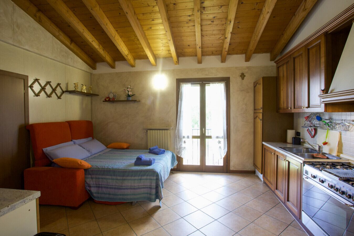 A cozy bedroom with a bed, a small sofa, and a kitchenette with a stove.