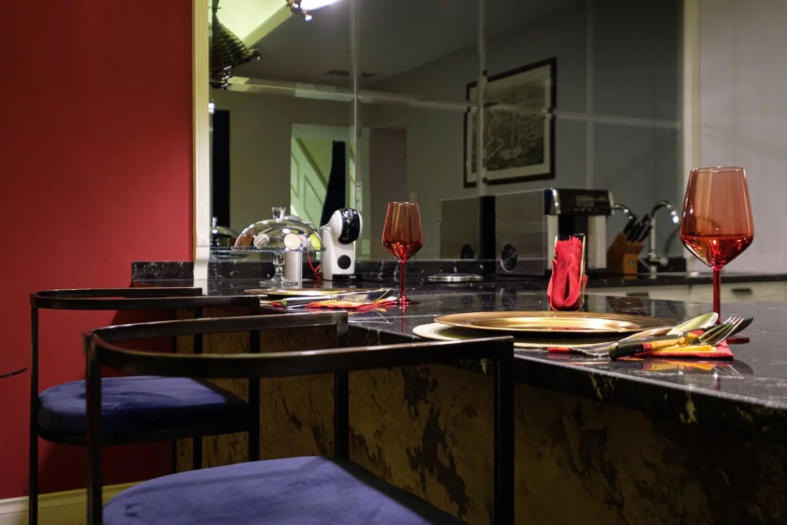 Un coin repas doté d’un comptoir en marbre, de deux chaises et d’une table mise avec des assiettes, des verres et des couverts.