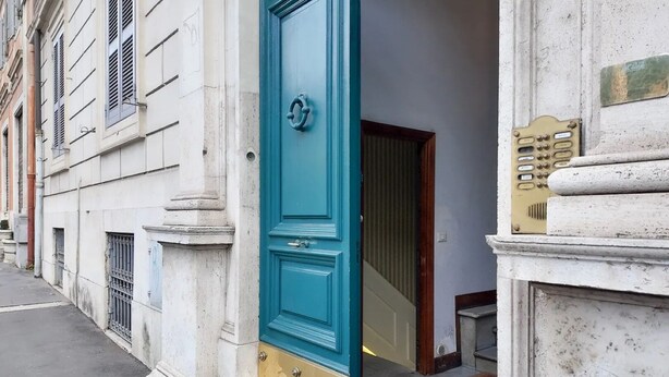 A building with a blue door, a metal grille, and a small step leading to the entrance.