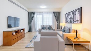 Un salon moderne avec un ensemble de canapés, un téléviseur, un meuble en bois et un tableau accroché au mur.