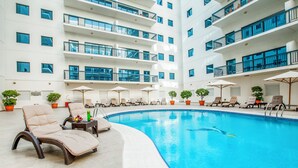 Un hôtel moderne doté d’une grande piscine intérieure, de nombreux balcons et de chaises longues.