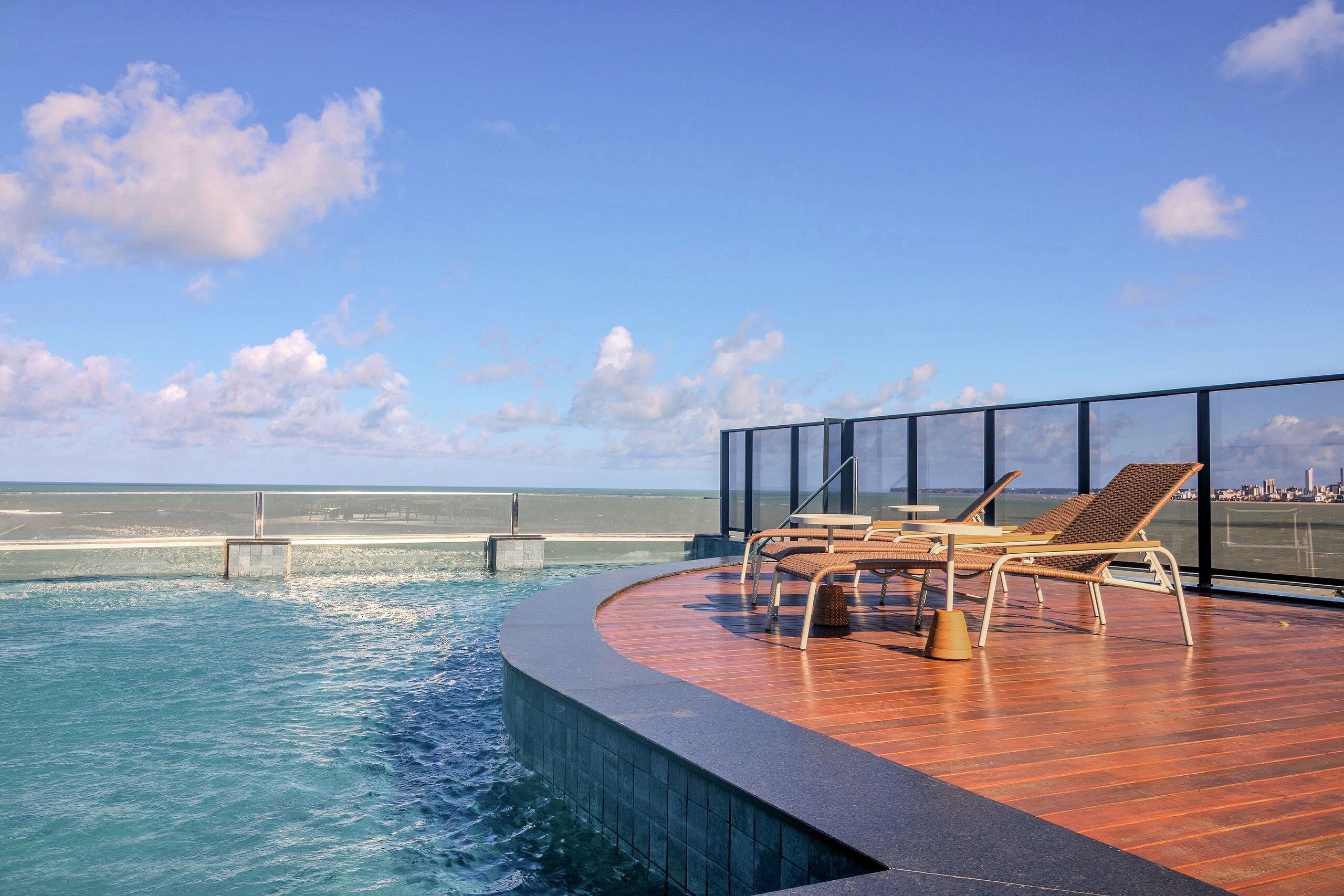 Zona de piscina con sillones de descanso y vistas al mar.