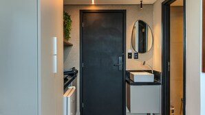 A modern bathroom with a dark door, a white sink, and a mirror. - Alta Marine (João Pessoa)
