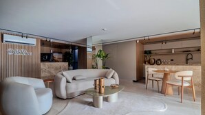 A modern living room with a sofa, a coffee table, and a dining area with chairs and a table. - Alta Marine (João Pessoa)