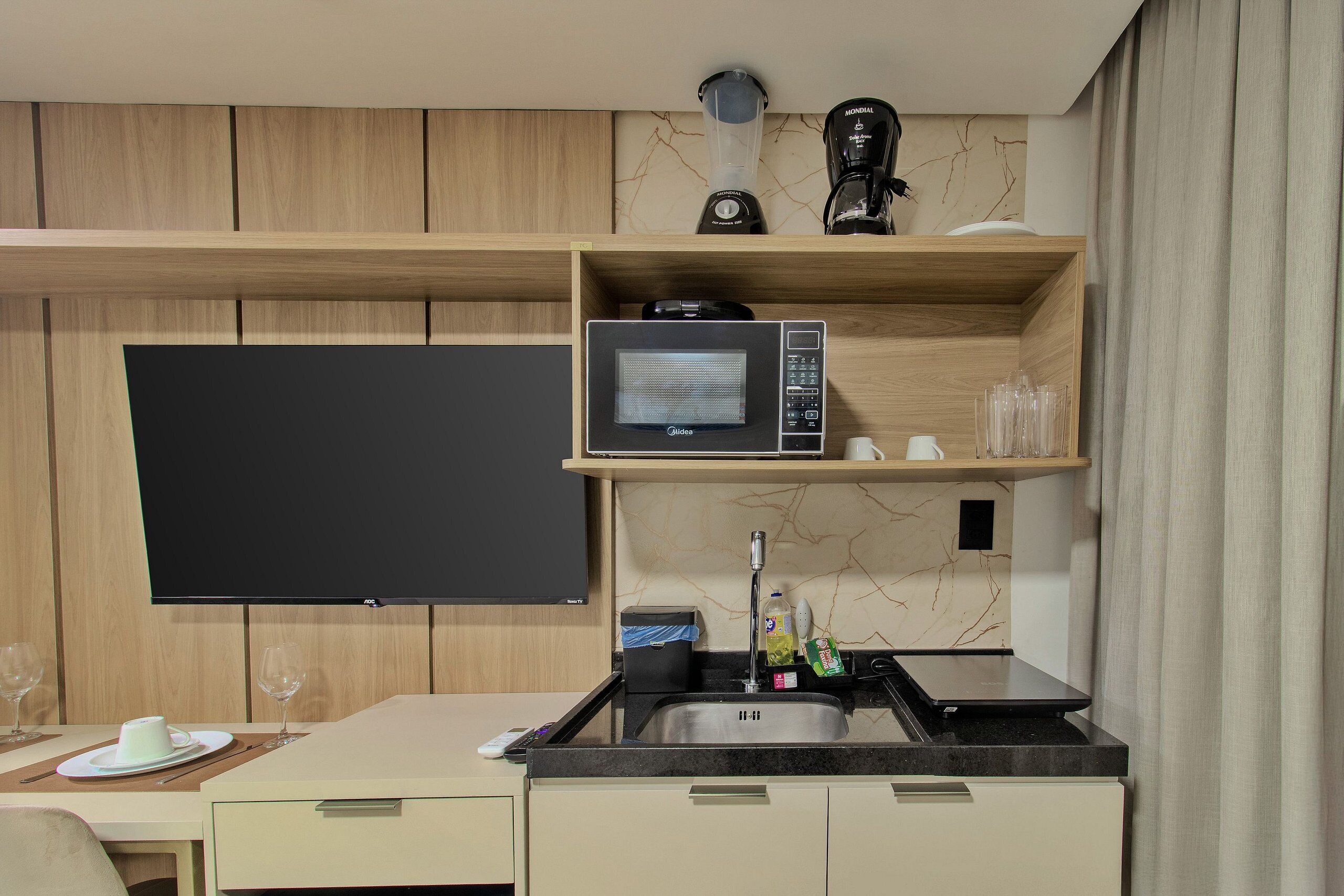 A modern kitchen with a microwave, coffee maker, and a flat-screen TV.