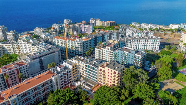 Un quartier résidentiel situé sur la côte, avec des immeubles à plusieurs étages, dont certains sont dotés de balcons, et offrant une vue dégagée sur la mer.