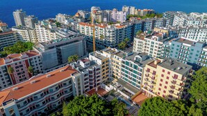 Un ensemble immobilier résidentiel de grande hauteur, doté de nombreux balcons, d’une cour intérieure et offrant une vue sur la mer.