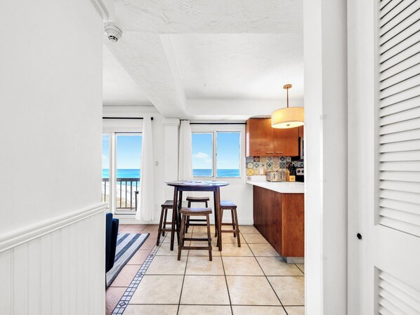 A narrow hallway leading to a kitchen with a view of the ocean.