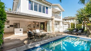 Una casa de dos pisos con piscina, comedor y cocina.