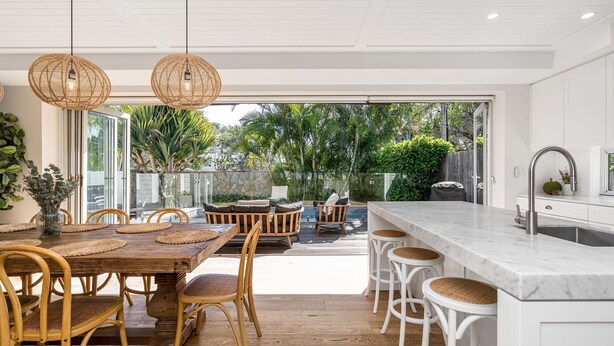 Una cocina moderna con encimera de mármol, muebles blancos y una isla grande con taburetes de bar.