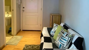 A living room with a sofa, a clock on the wall, a door, and a small cabinet. - Azure Urban Resort Residences (Parañaque)