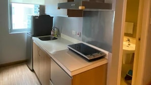 A compact kitchen with a built-in oven, a microwave, and a sink. - Azure Urban Resort Residences (Parañaque)