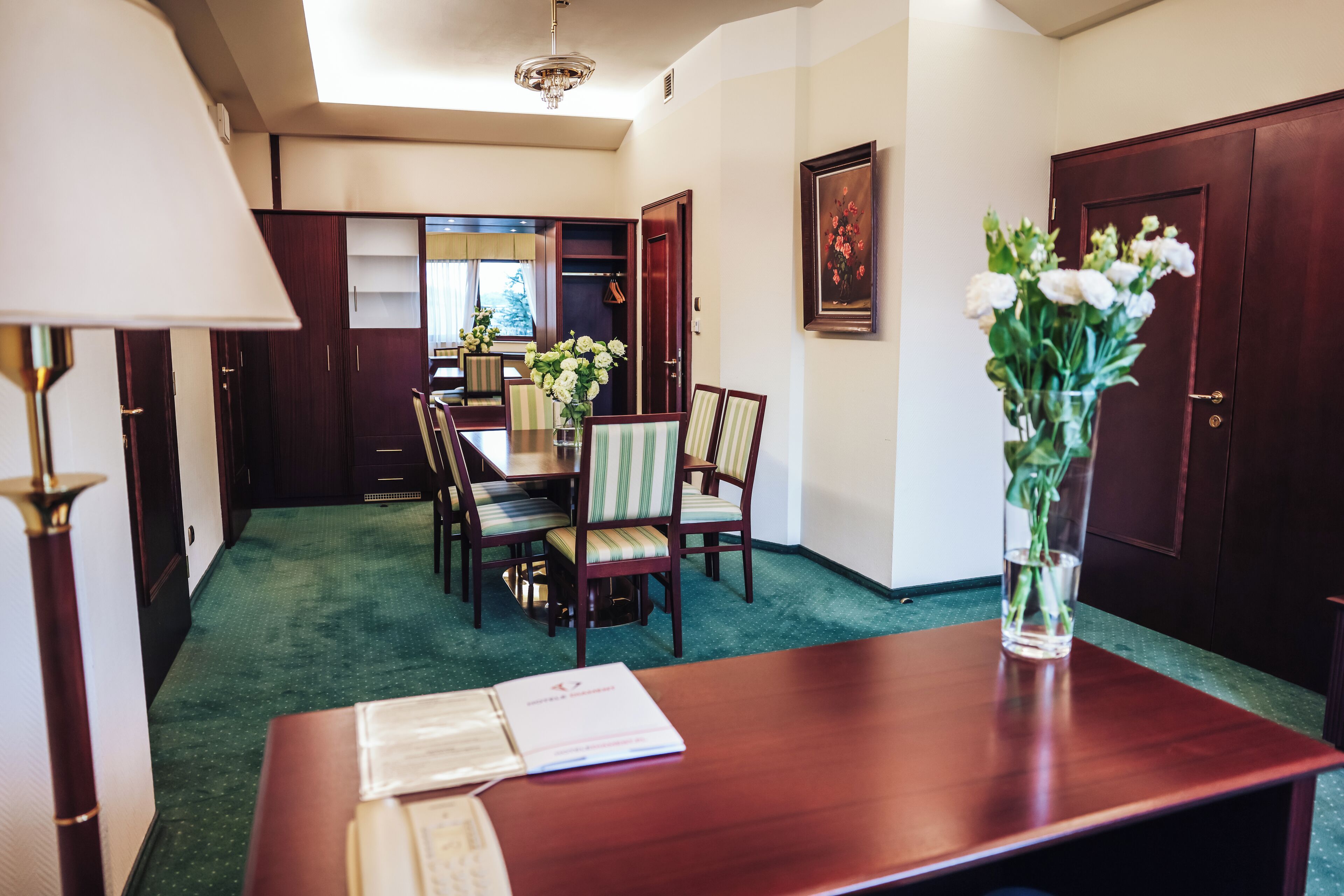 A dining area with a wooden table, chairs, and a vase of flowers.