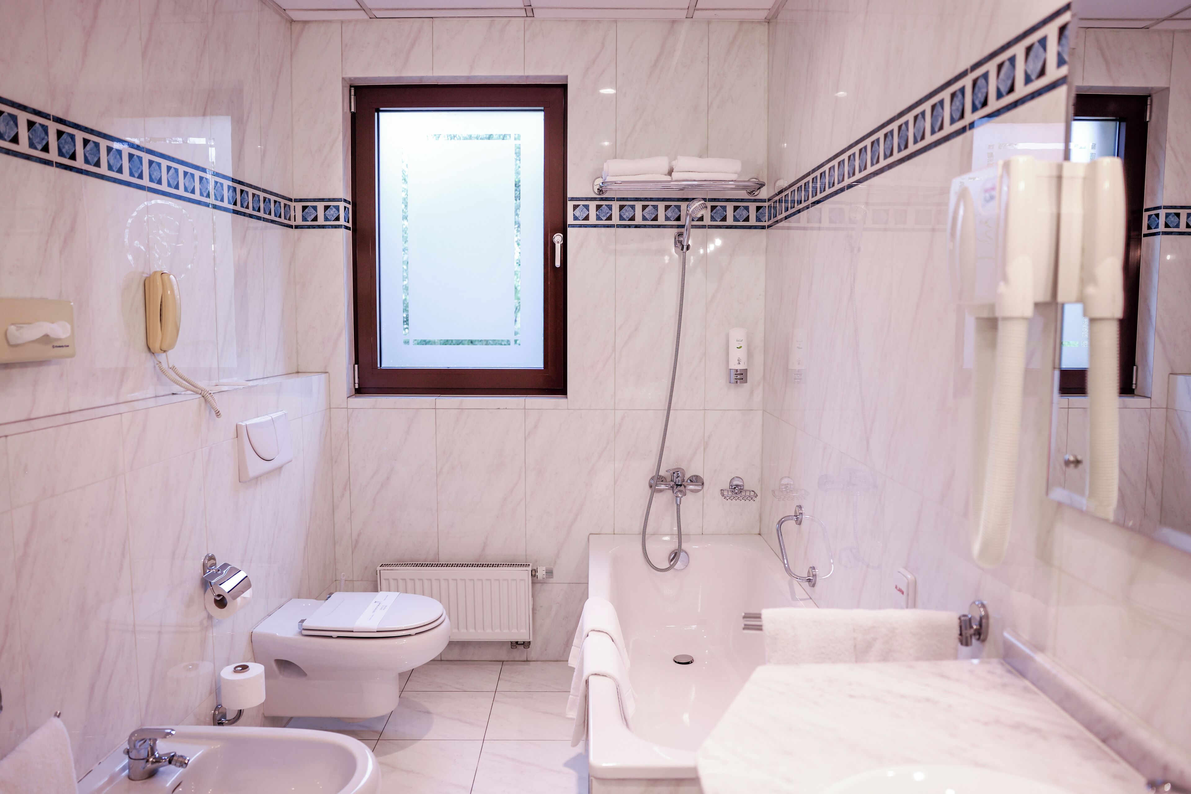 A modern bathroom with a toilet, bidet, sink, and bathtub.