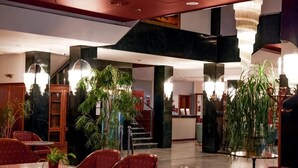 A spacious lobby with a high ceiling, a staircase, and several potted plants.