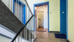A staircase with a metal handrail, a blue door frame, and a tiled floor. - Apartment "Apartment in Hannover Mitte" with Wi-Fi (Hannover)