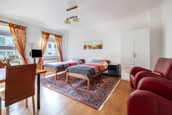 Une chambre à coucher moderne, comprenant un lit, un bureau, une chaise, une armoire et un téléviseur.