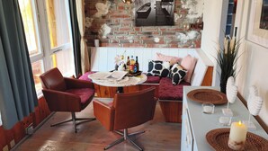 A cozy room with a wooden ceiling, a brick wall, a dining table with chairs, and a bar area with a candle.
