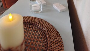 Un espace repas avec un mur en briques, des suspensions lumineuses et une vue sur un bateau représenté dans un tableau.