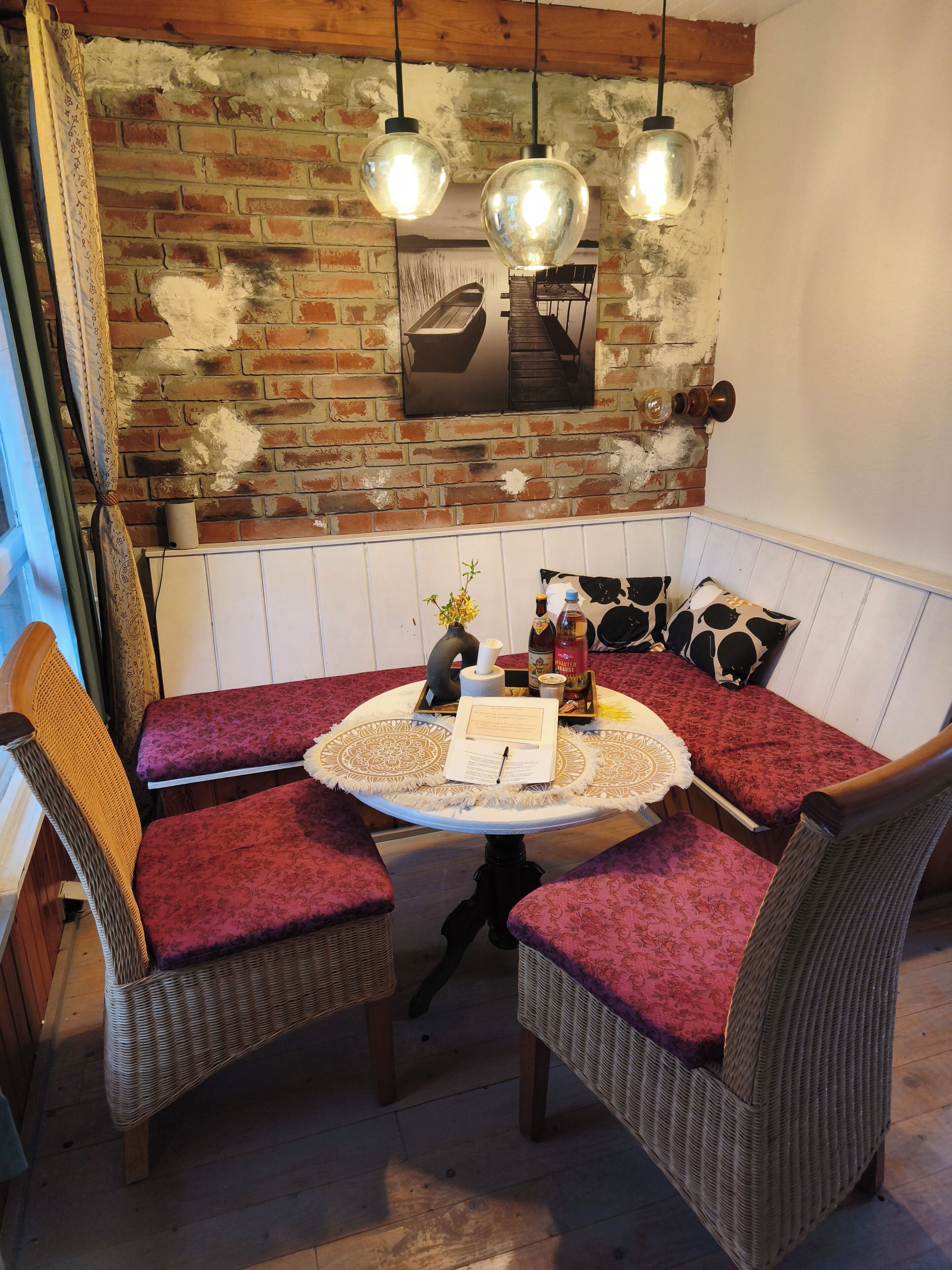 A cozy dining area with a round table, wicker chairs, and a brick wall backdrop.