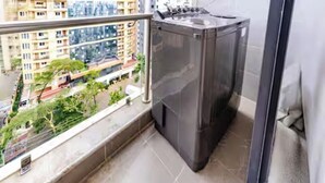 Un balcó amb vista a un paisatge urbà, una rentadora i un sòl de rajola.