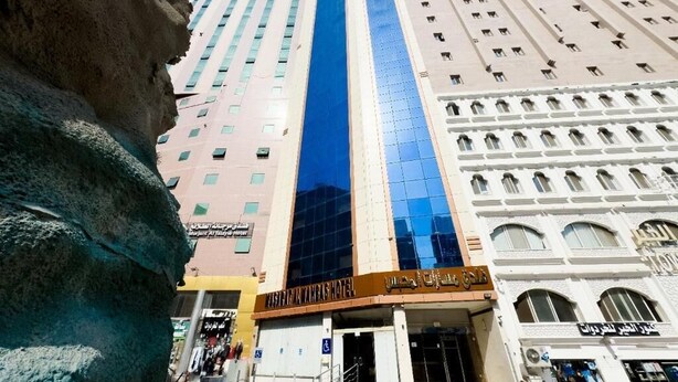 A hotel with a prominent blue glass facade, multiple floors, and a traditional architectural style with arched windows.