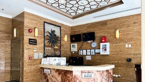 A reception area with a marble counter, a reception sign, a clock, and a television mounted on the wall.