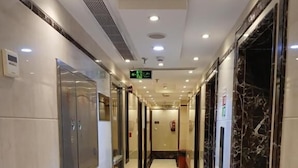 A hotel corridor with marble flooring, a long hallway, and doors leading to rooms.
