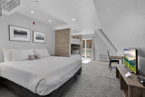 A bedroom with a large bed, a TV, and framed pictures on the wall. - Selkirk Bungalow - Sleeps 8 Family-Friendly Suite (Sandpoint)