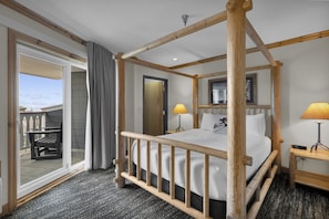 Un lit à baldaquin avec un cadre en bois, une petite table de chevet avec une lampe, une grande fenêtre donnant sur un paysage agréable et une porte menant à un espace extérieur.